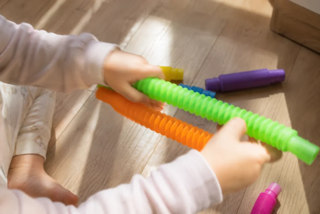 Toddler hands stretching a colorful pop tube sensory toy